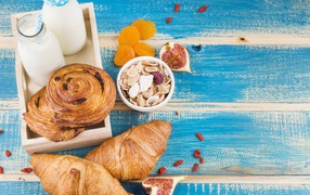 Свежая выпечка, молоко и мюсли на завтрак на столе