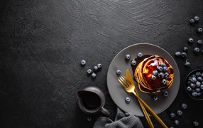 Оладьи с шоколадом на черном столе с ягодами черники