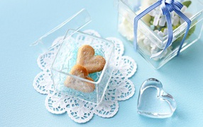 Песочное печенье в форме сердца в стеклянной шкатулке на голубом столе 