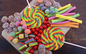 Разноцветные желейные конфеты, мармелад и леденцы на палочке на столе
