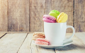 Разноцветный десерт макарон в белой чашке на столе