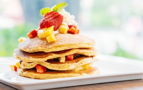 Оладьи с сахарной пудрой, сливками и кусочками клубники и ананаса