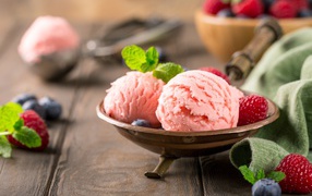 Шарики фруктового мороженого на столе с ягодами малины и черники 
