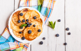 Румяные оладьи на тарелке с ягодами черники