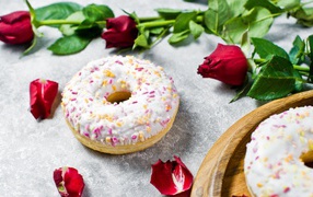 Сладкий пончик с глазурью на столе с красными розами