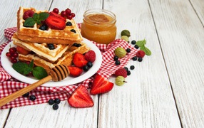 Сладкие вафли на столе с ягодами и медом