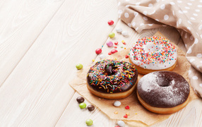 Три аппетитных пончика с глазурью на столе 