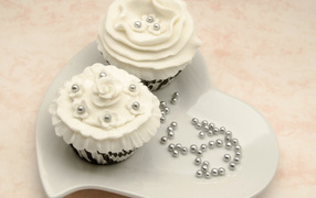 Two cupcakes to white cream on a heart shaped plate  