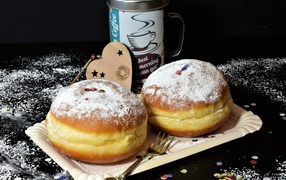Два пышных пончика с сахарной пудрой на черном столе с кофе