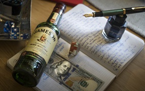 A bottle of whiskey lies on a notebook with an inkwell and a bill.