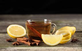 Чашка чая на столе с корицей и кусочками лимона 