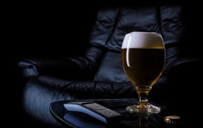 A glass of beer on the background of a black leather chair