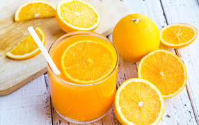 Стакан апельсинового сока на столе со свежими апельсинами на столе