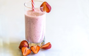 Стакан клубничного смузи на белом фоне с ягодами