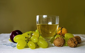 A glass of white wine on the table with grapes and nuts