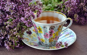 Красивая чашка чаю с цветами мяты на столе