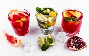 Стаканы с цитрусовыми коктейлями со льдом на белом фоне с фруктами