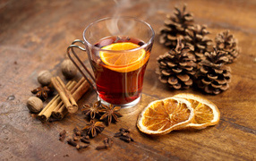 Чай с лимоном в чашке на столе с корицей, бадьяном и шишками
