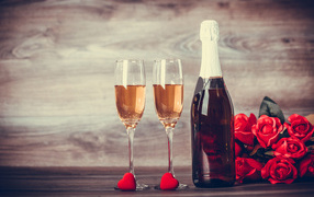Два бокала и бутылка шампанского на столе с букетом роз