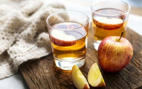 Два стакана сока на столе с яблоками 