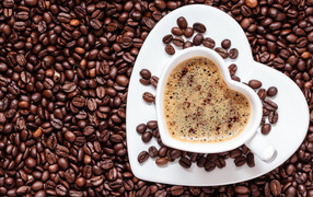 Белая чашка в форме сердца стоит на кофейных зернах 