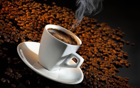 Белая чашка с кофе на черном фоне с кофейными зернами 