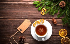 White cup of tea with star anise on a wooden background with a branch of spruce and dried orange