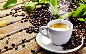 White cup with hot coffee on a wooden table with coffee beans