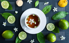 Белая чашка с чаем на столе с лаймом и зелеными листьями 