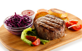 Кусок мяса гриль на доске с салатом и овощами