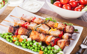 Appetizing ruddy skewers with green peas on a plate