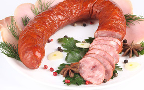 Appetizing sausage on a white background with spices and greens