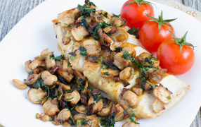 Appetizing slice of chicken fillet with mushrooms on a plate with tomatoes