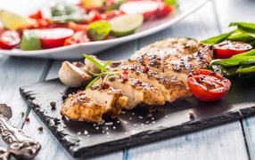 Запеченное куриное мясо на доске с помидорами 