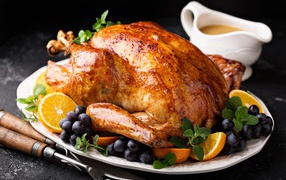 Baked chicken on a plate with oranges and berries