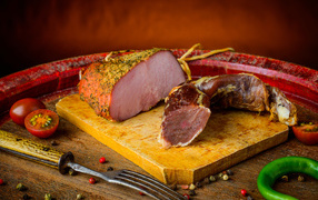 Ветчина и вяленое мясо на разделочной доске на столе с помидорами и горьким перцем 