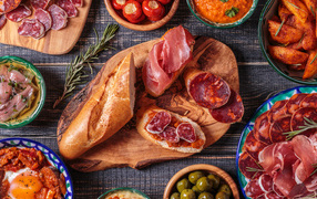 Бутерброды с ветчиной на столе с мясными закусками и консервацией