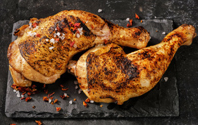 Two baked chicken legs on a black background