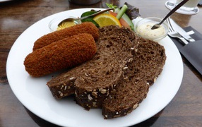 Two pieces of black bread on a plate of chops