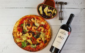 Pizza on the table with olives and a bottle of wine