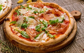 Pizza with fish and arugula on a cutting board