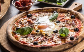 Pizza with ham, mushrooms, olives and fried eggs