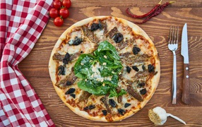 Pizza with meat and spinach on the table
