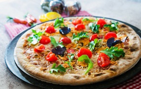 Pizza with tomatoes, arugula and cheese on the table