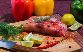 Кусок сырой рыбы на разделочной доске со специями, лимоном и болгарским перцем