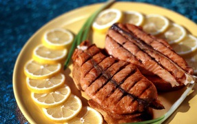 Зажаренная красная рыба с кусочками лимона и зеленым луком
