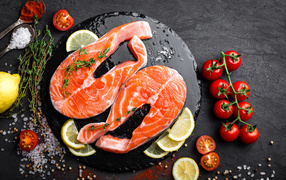 Два куска красной рыбы с овощами на черном фоне