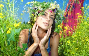 Молодая девушка с венком из полевых цветов лежит в траве