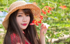 Девушка азиатка в шляпе с красным цветком