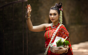 Девушка азиатка в костюме стоит у железных ворот
